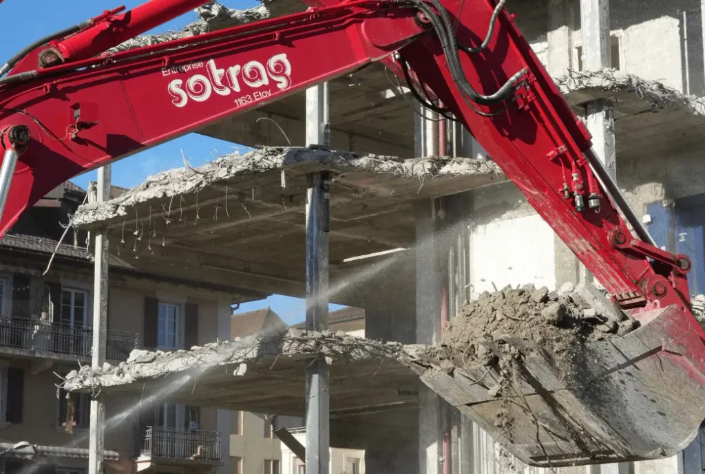 Photo d'une machine rouge Sotrag en train de démolir le bâtiment de l'hôpital de l'enfance